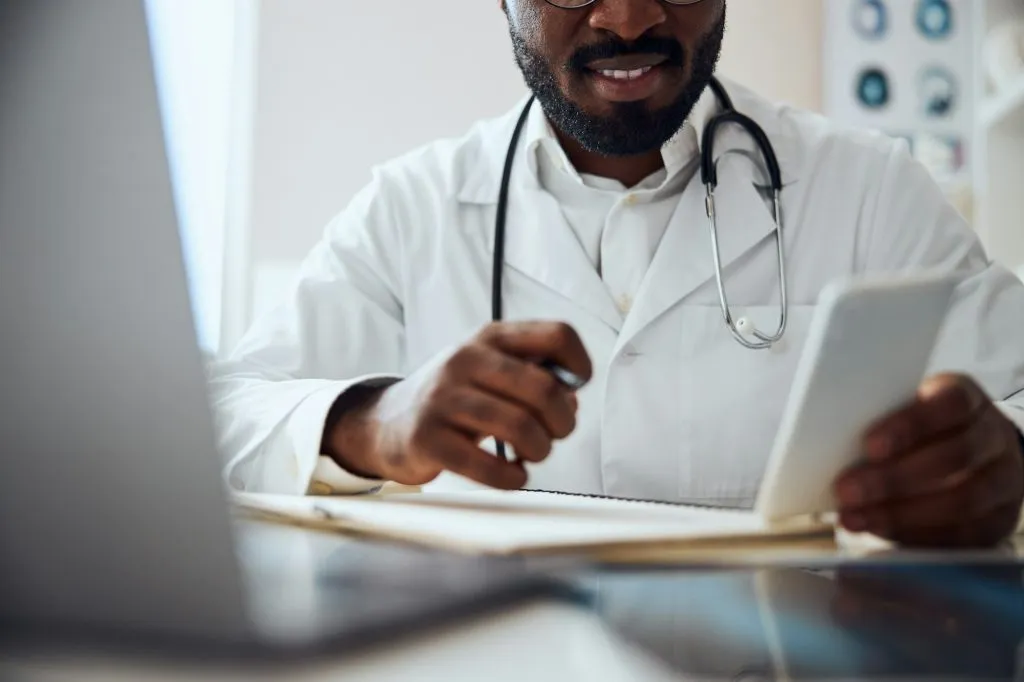 smiling medical practitioner is using a smartphone