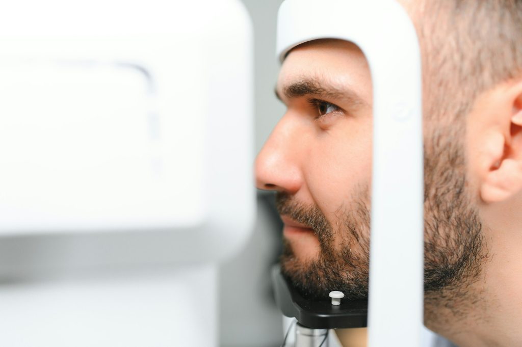 handsome man getting an eye exam at ophthalmology clinic checking retina of a male eye