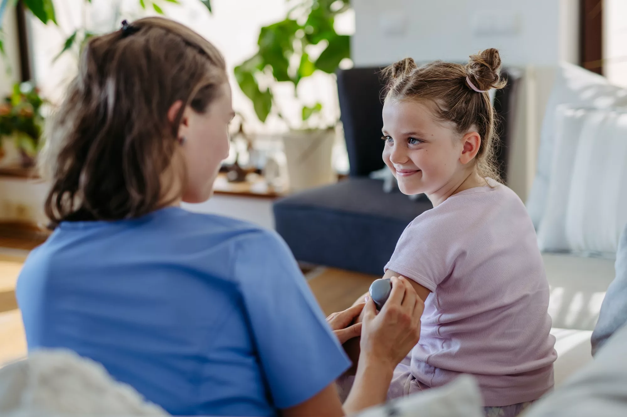 Nurse applying a continuous glucose monitor sensor to the arm of a diabetic girl.